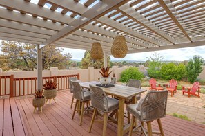 An outdoor patio with a pergola, wicker chairs, a table, and potted plants. - Luxe Mesa View Home on 35 Acres w/ Wraparound Deck (Glade Park)