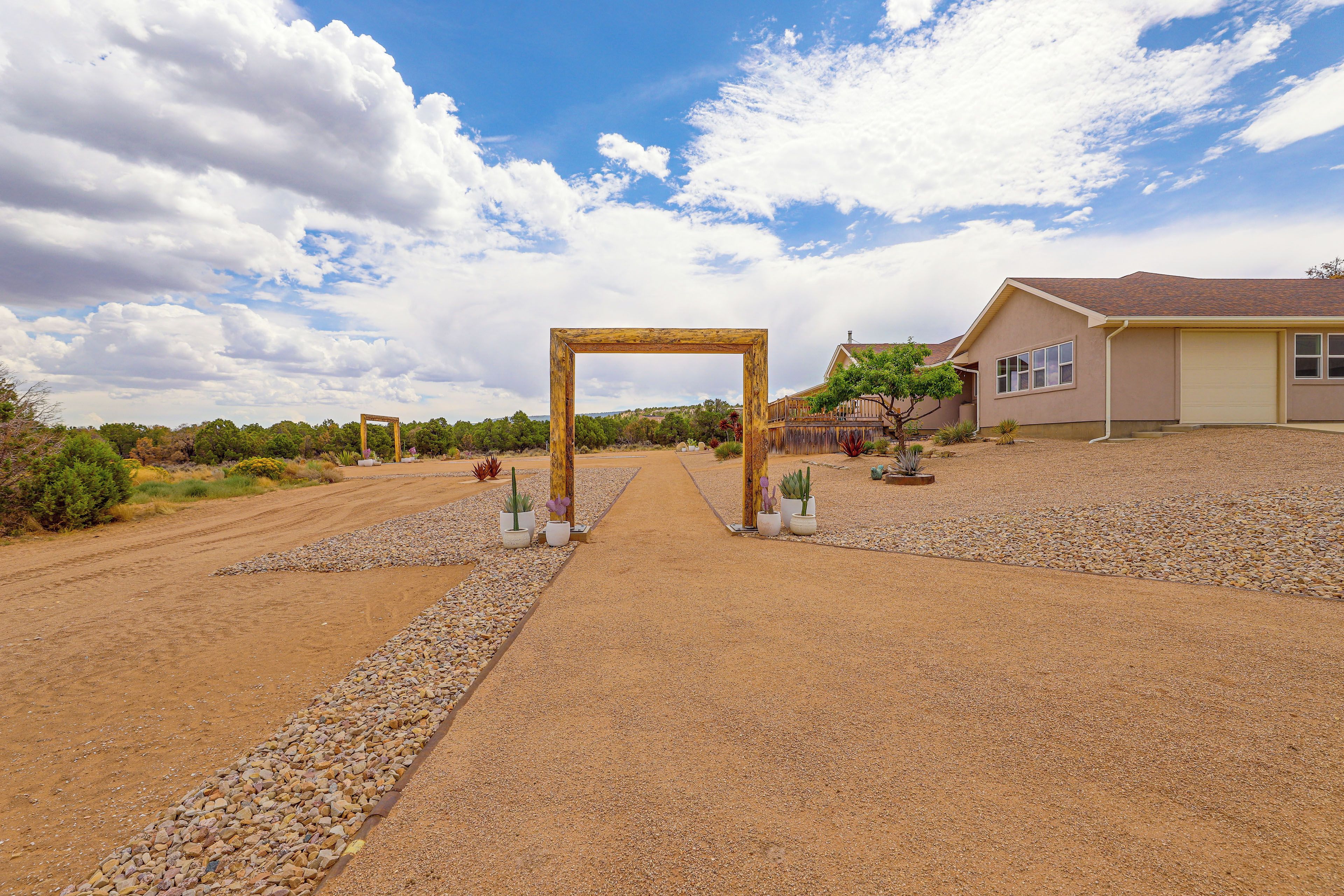 Una casa con camino de grava que conduce a un arco de madera.