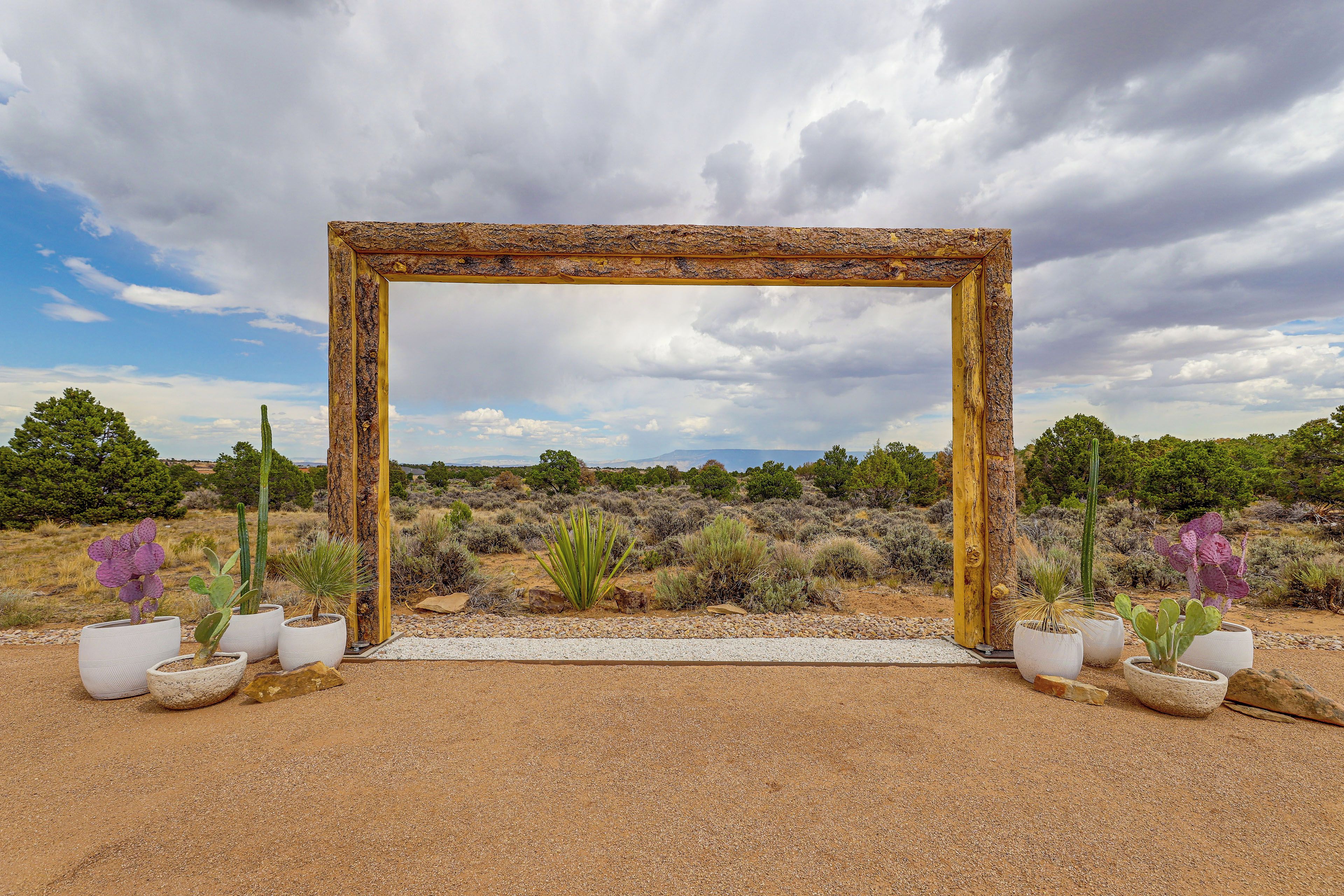 A rustic wooden frame structure in a desert landscape with cacti and shrubs.