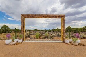 A rustic wooden frame structure in a desert landscape with cacti and shrubs. - Luxe Mesa View Home on 35 Acres w/ Wraparound Deck (Glade Park)