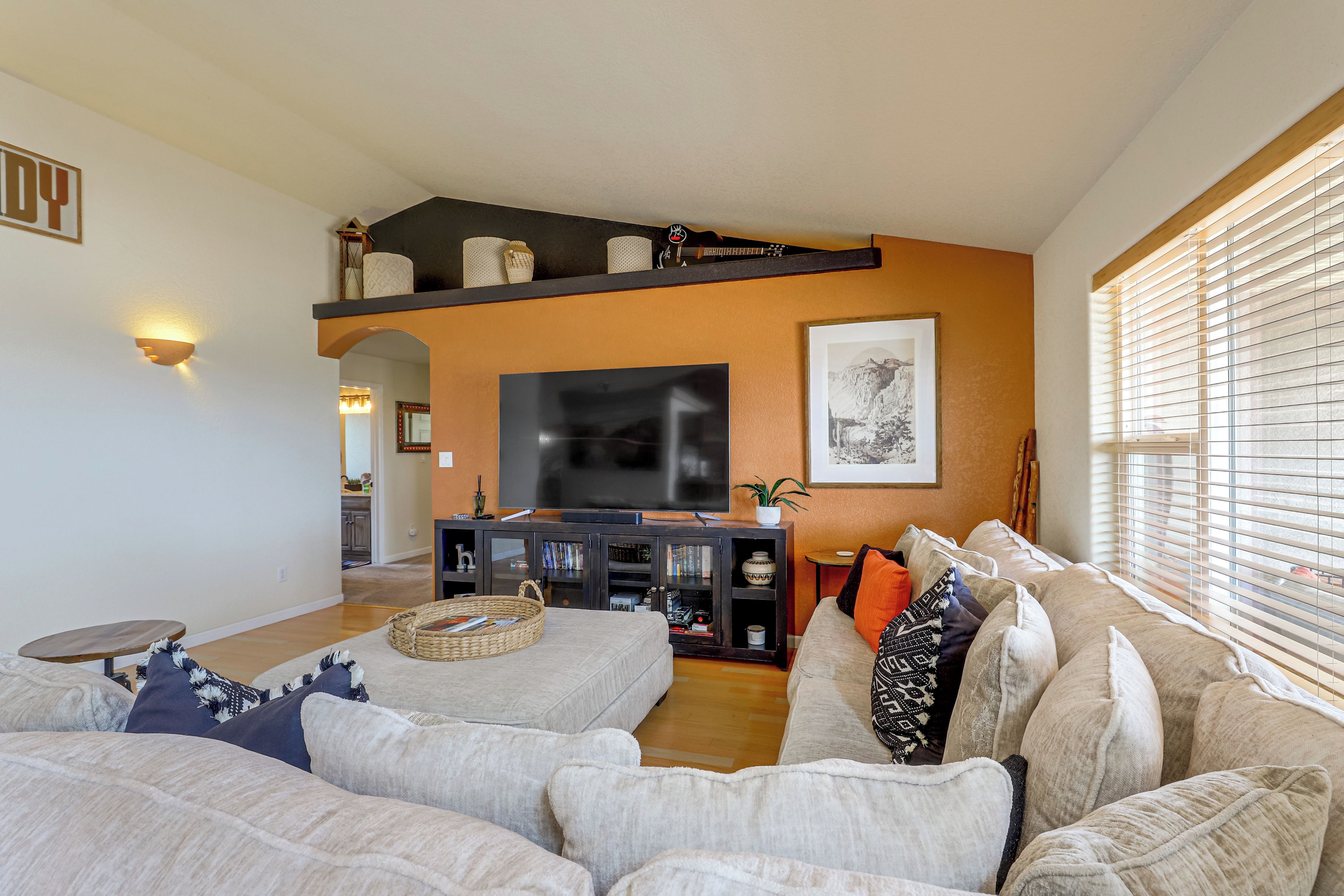 A living room with a large sofa, a television, and a bookshelf.