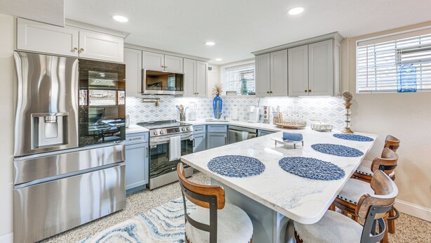 A modern kitchen with stainless steel appliances, a central island with blue placemats, and light gray cabinetry. - 20 Mi to Pittsburgh: Natrona Heights Apt (Natrona Heights)