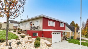 A two-story house with a red exterior, a garage, and a landscaped front yard with rocks and a small tree. - 20 Mi to Pittsburgh: Natrona Heights Apt (Natrona Heights)