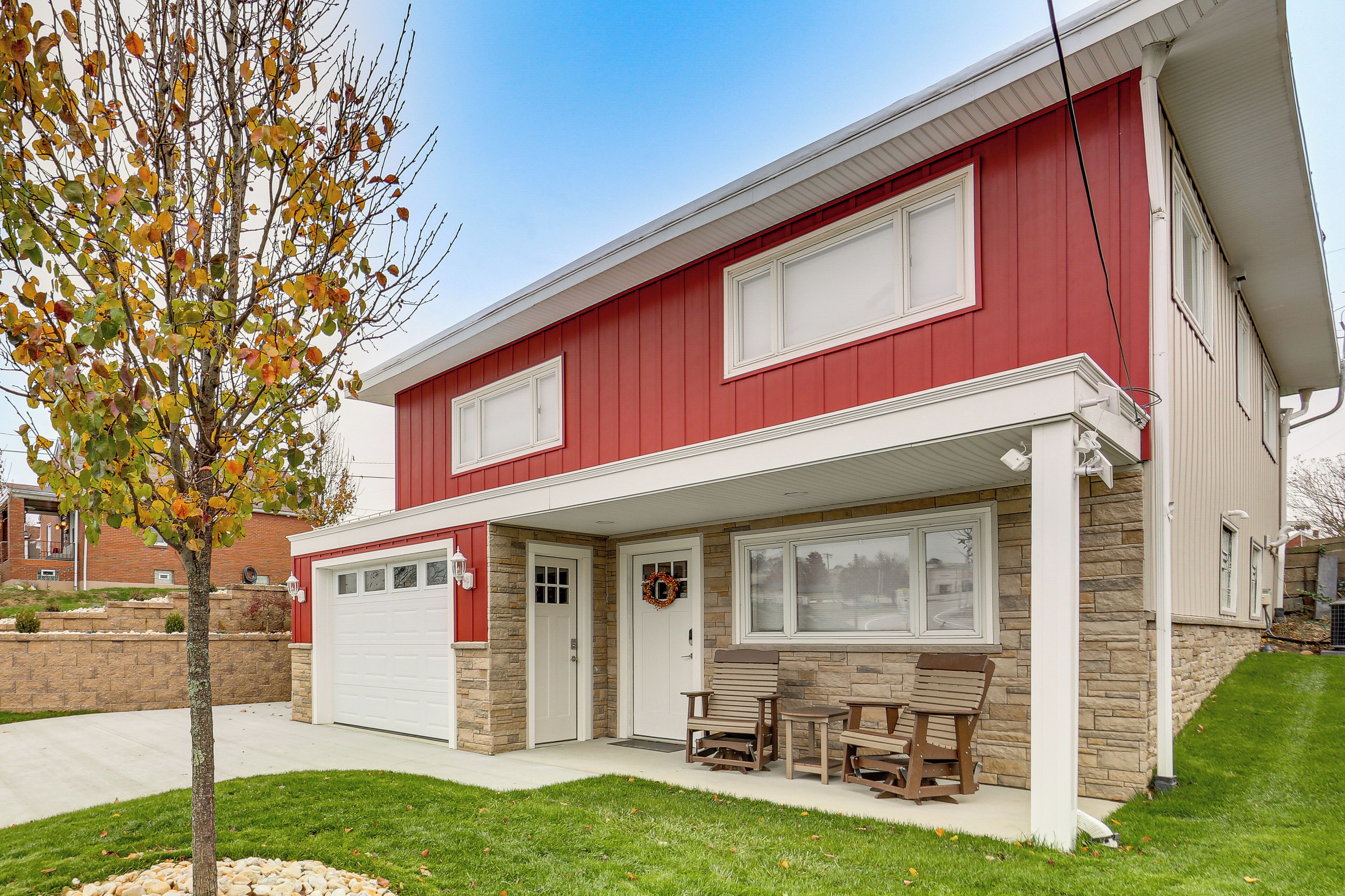 A two-story house with a red exterior, a garage, and a covered porch with outdoor furniture.