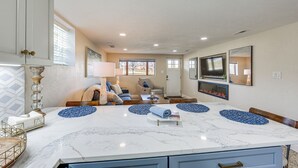 A spacious living room with a large marble dining table, comfortable seating, a fireplace, and a television mounted on the wall. - 20 Mi to Pittsburgh: Natrona Heights Apt (Natrona Heights)