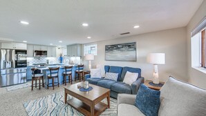A modern kitchen with a central island, a dining area with a wooden table, and a living room with a sofa and a lamp. - 20 Mi to Pittsburgh: Natrona Heights Apt (Natrona Heights)