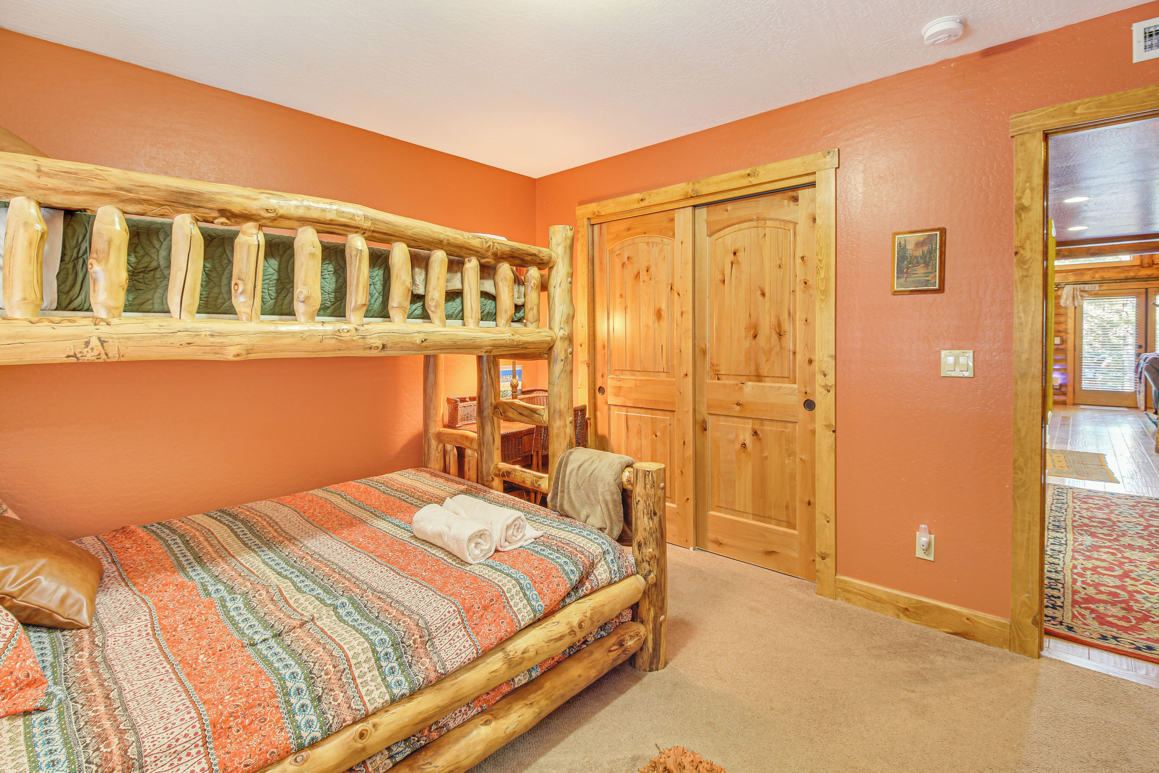 A room with a wooden bunk bed, a wooden wardrobe, and a carpeted floor.