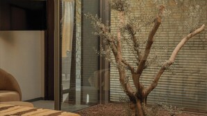 A bedroom with a bed, a glass door leading to a balcony with a tree and a stone wall. - Silence Villas (Fethiye)