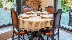A dining table set for four with a bottle of Cado wine, surrounded by leather chairs and a stone wall in the background. - Garden retreat near Porto (Porto)