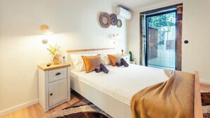 A bedroom with a bed, bedside table, wall decor, and a window. - Garden retreat near Porto (Porto)