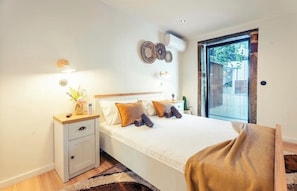 A bedroom with a bed, bedside table, wall decor, and a window.