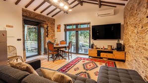 A cozy living room with a stone wall, a large TV, and a dining area with a table and chairs. - Garden retreat near Porto (Porto)