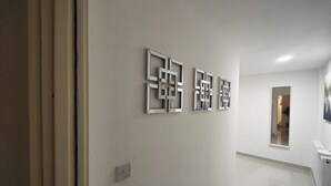 Um corredor com design moderno, apresentando uma série de obras de arte geométricas na parede e um interruptor de luz.