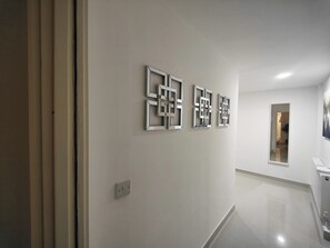 Un couloir au design moderne, agrémenté d’une série d’œuvres d’art murales aux motifs géométriques et d’un interrupteur.