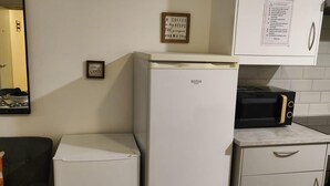 Uma cozinha compacta com geladeira branca, torradeira preta e um armário com as regras da cozinha.