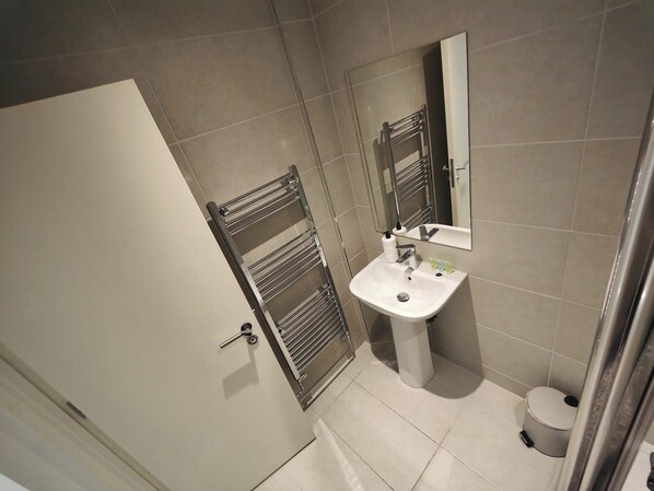 Une salle de bain avec un lavabo blanc, un miroir et un porte-serviettes.