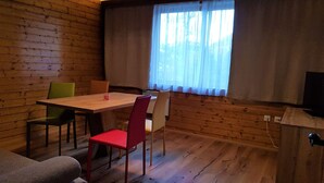 A cozy room with a wooden floor, a dining table with chairs, a sofa, and a window with curtains. - Nature & Ski Retreat in Bad Kleinkirchheim (Bad Kleinkirchheim)