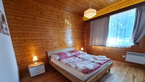 A wooden cabin bedroom with a bed, bedside lamps, and a window with curtains. - Nature & Ski Retreat in Bad Kleinkirchheim (Bad Kleinkirchheim)