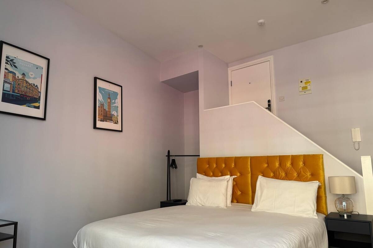 A bedroom with a bed, a nightstand, a lamp, and two framed pictures on the wall.