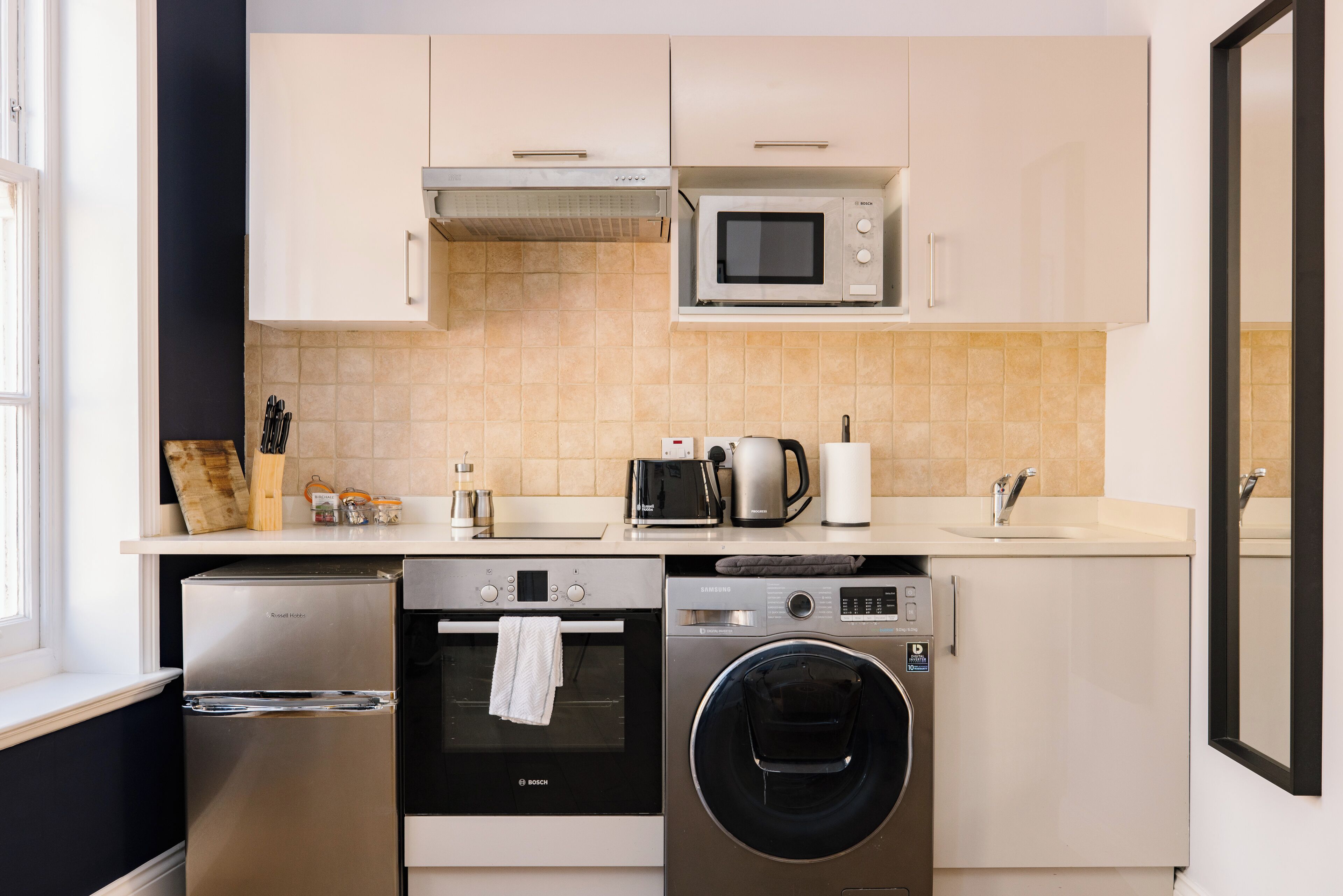 Cozinha compacta com micro-ondas, torradeira e cafeteira. Possui também máquina de lavar louça e máquina de lavar roupa.
