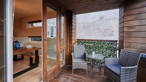 An outdoor patio with a wooden table and chairs, a glass door leading to a room, and a view of buildings in the background. - Host Stay Ropewalks Quarters VI (Liverpool)