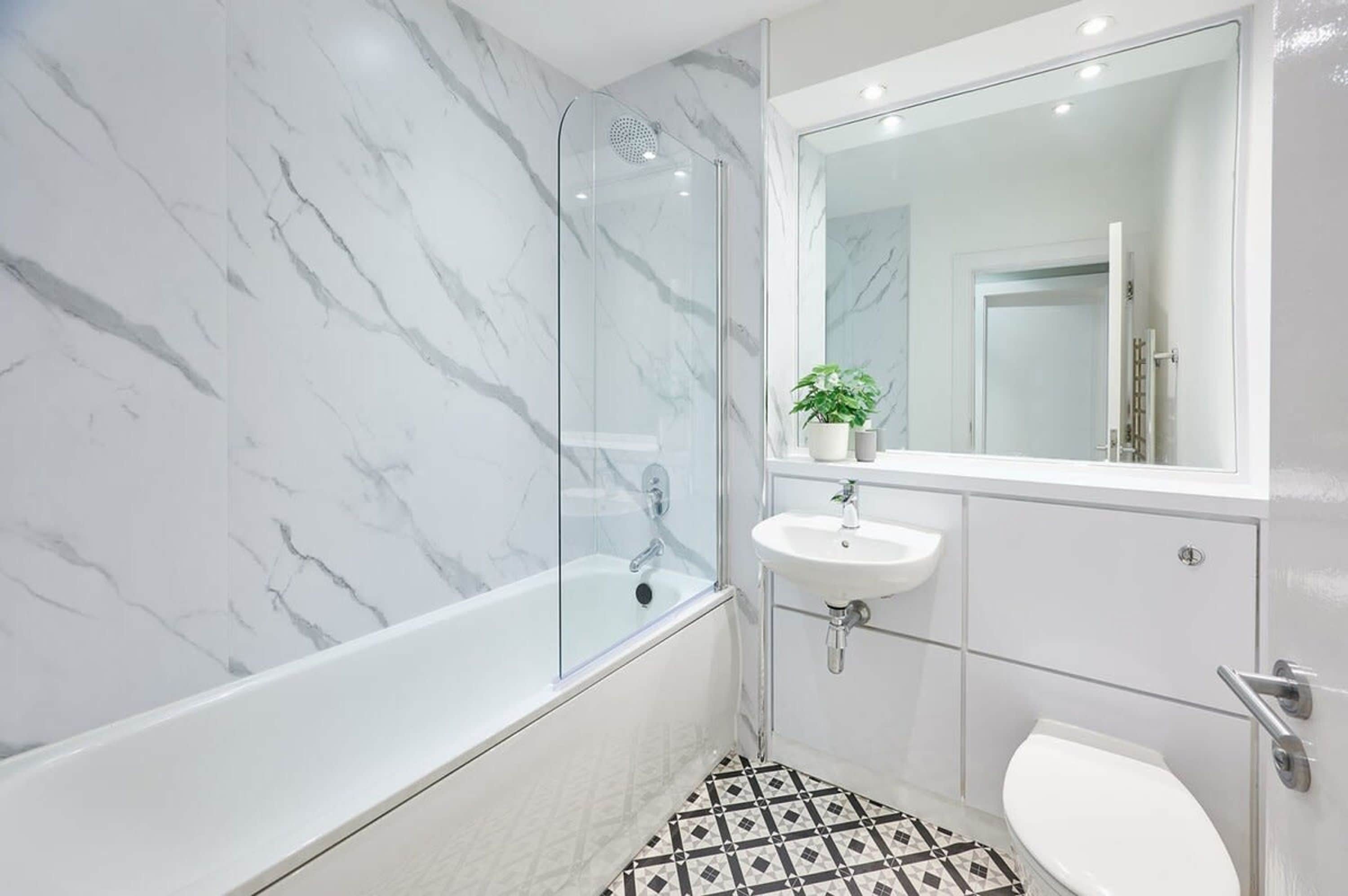 A modern bathroom with a glass-enclosed shower, a white sink, and a toilet.