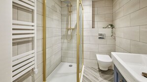 Een moderne badkamer met een inloopdouche, toilet en een bad.