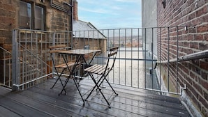 A balcony with a table and chairs, a metal railing, and a view of the cityscape. - Host Stay Sea Salt Apartment (Whitby)