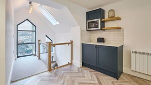 A modern kitchen with a skylight, dark cabinets, and a herringbone floor. - Host Stay Sea Salt Apartment (Whitby)