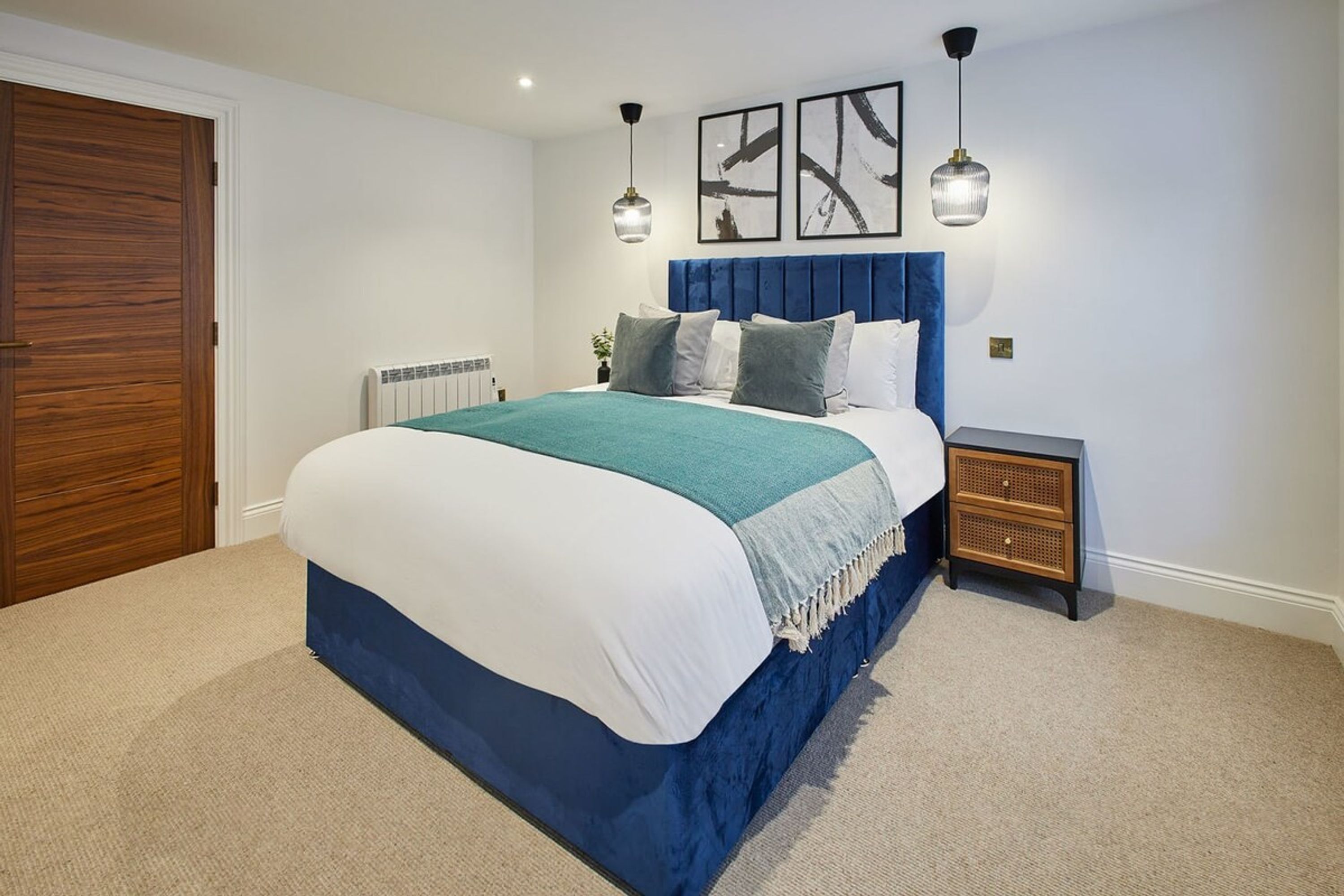 A bedroom with a bed, a nightstand, a wooden door, and a radiator.