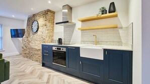 A modern kitchen with a stone accent wall, built-in oven, and a large clock. - Host Stay Sea Salt Apartment (Whitby)