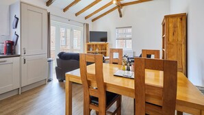 A cozy dining area with wooden furniture, a television on a stand, and a window with blinds. - Host Stay Jubilee Close (Filey)