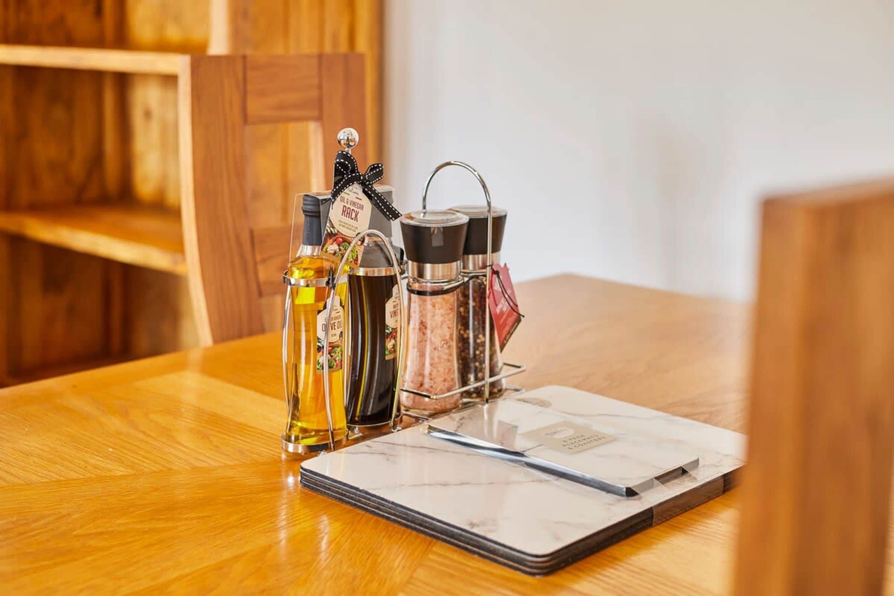 A wooden table with a marble notebook, a pen, and a spice rack with various bottles and containers.
