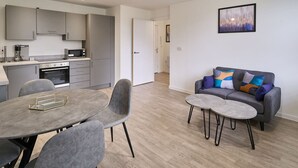 A modern kitchen with grey cabinets, a microwave, and a dining area with a grey table and chairs. - Host Stay 23 Waterside Place (Taunton)