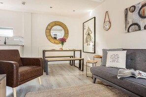 A modern living room with a brown leather sofa, a grey couch, a wooden coffee table, and a round mirror on the wall. - Host Stay Slater Street Apartments V (Liverpool)