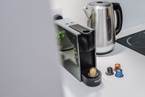 Una cocina moderna con una cafetera, un hervidor y una pequeña planta.