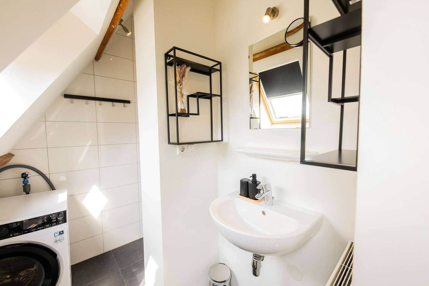 Un baño moderno con lavadora, lavabo y espejo.