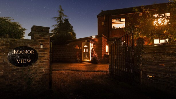 A brick building with a sign reading "MANOR VIEW" at night, under a starry sky. - Host Stay Pied-a-terre at Manor View (Bury)
