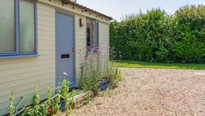 A single-story building with a front door, a small porch, and a gravel driveway. - Host Stay Hen Barn (Norwich)