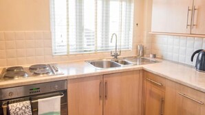 Una cocina con estufa, horno, pileta y alacenas.