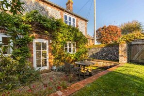 A stone house with a brick exterior, a garden with a table and chairs, and a stone wall.