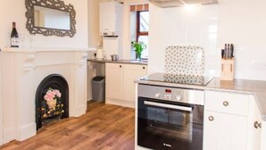A kitchen with a built-in oven, a microwave, and a gas stove. There is a white cabinet with a patterned backsplash, and a mirror above the counter.