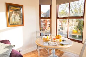 Un comedor con una mesa lista para el desayuno, un cartel en la pared y vistas a la calle.