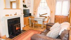Un salon chaleureux avec une cheminée, un téléviseur, un bureau et un canapé confortable.