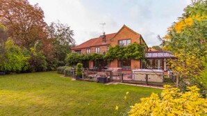 A brick house with a red roof, surrounded by a well-maintained lawn and various trees. - Host Stay Four Seasons (Norwich)