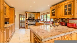 A spacious kitchen with wooden cabinets, granite countertops, and a central island. - Host Stay Four Seasons (Norwich)