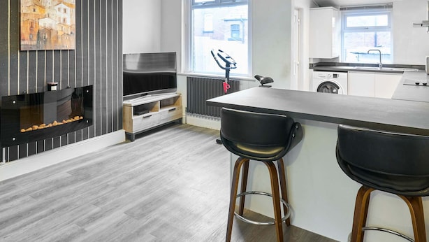 A modern kitchen with a central island, bar stools, a built-in oven, and a window with a view of the outside. - Host Stay Thurstane Street (Bolton)