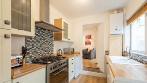 A modern kitchen with white cabinetry, a tiled backsplash, a gas stove, and a built-in oven. - Host Stay Wind Rose Cottage (Morpeth)