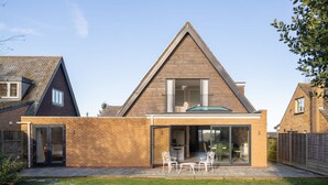A modern house with a large patio, a dining area, and a covered outdoor kitchen. - Host Stay High Gables (Northampton)