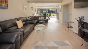 A modern living room with a sectional sofa, a glass coffee table, and a fireplace. - Host Stay High Gables (Northampton)